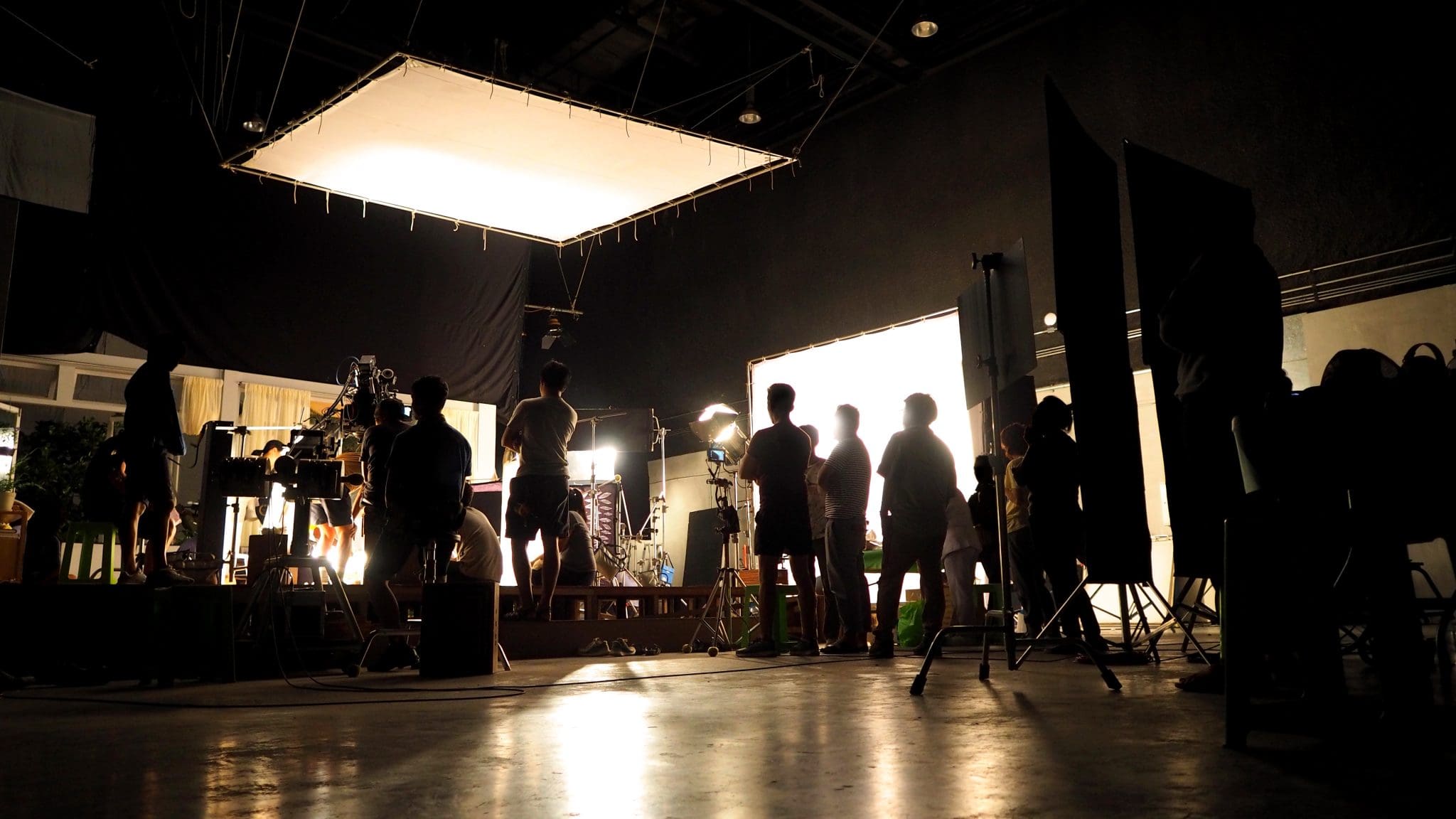 Behind the scenes of video shooting production crew team silhouette and camera equipment in studio.